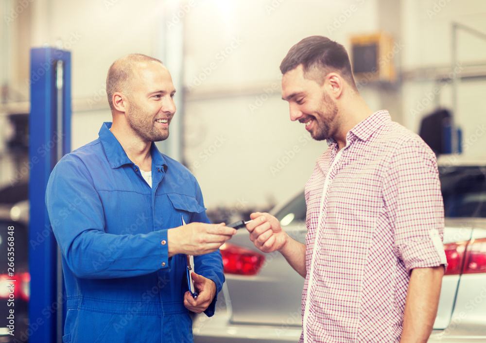 auto service, repair, maintenance and people concept - mechanic with clipboard giving key to happy smiling man or owner at car shop auto service, repair, maintenance and people concept - mechanic with clipboard giving key to happy smiling man or owner at car shop