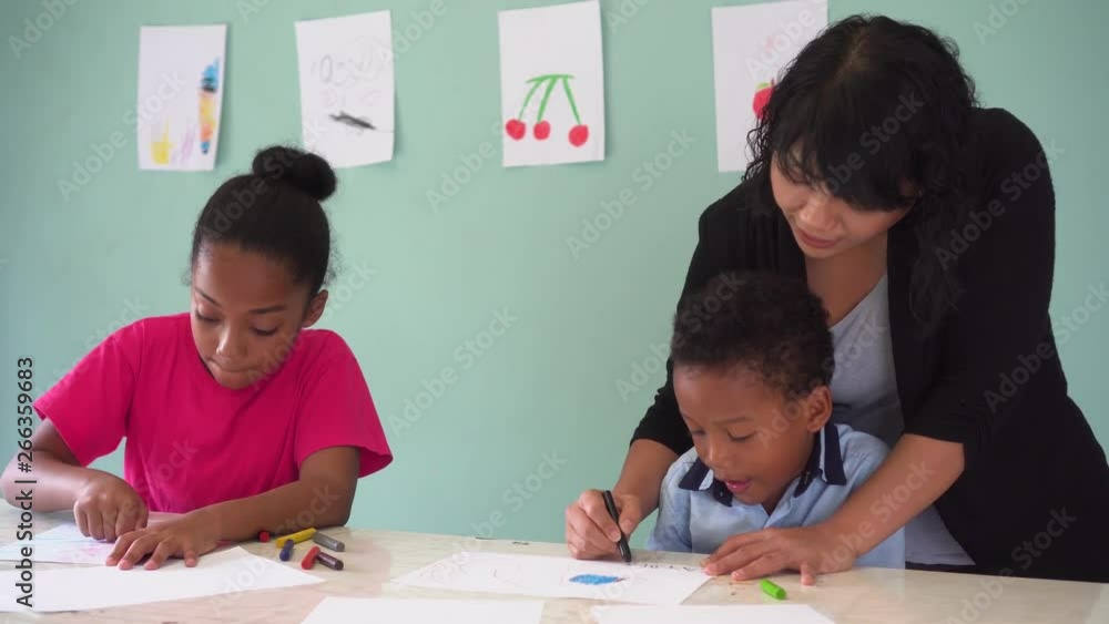 Young teacher giving African American kids an art lesson and teaching how to draw inside indoors room in natural ambient light Young teacher giving African American kids an art lesson and teaching how to draw inside indoors room in natural ambient light