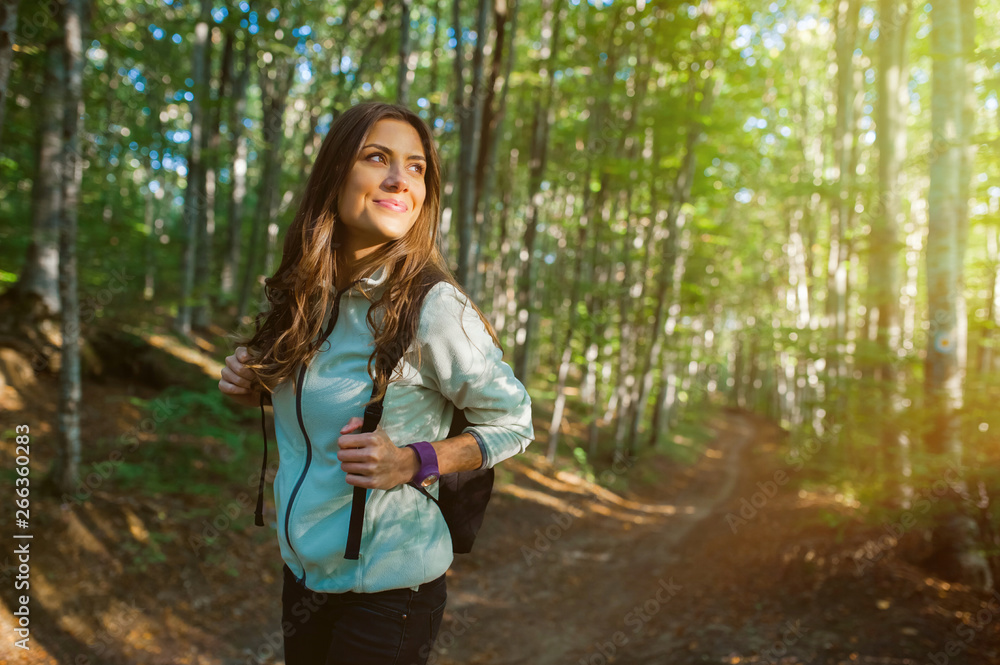 Φωτογραφία Young woman taking a walk in the forest, carrying a backpack in the forest on sunset light in the autumn season