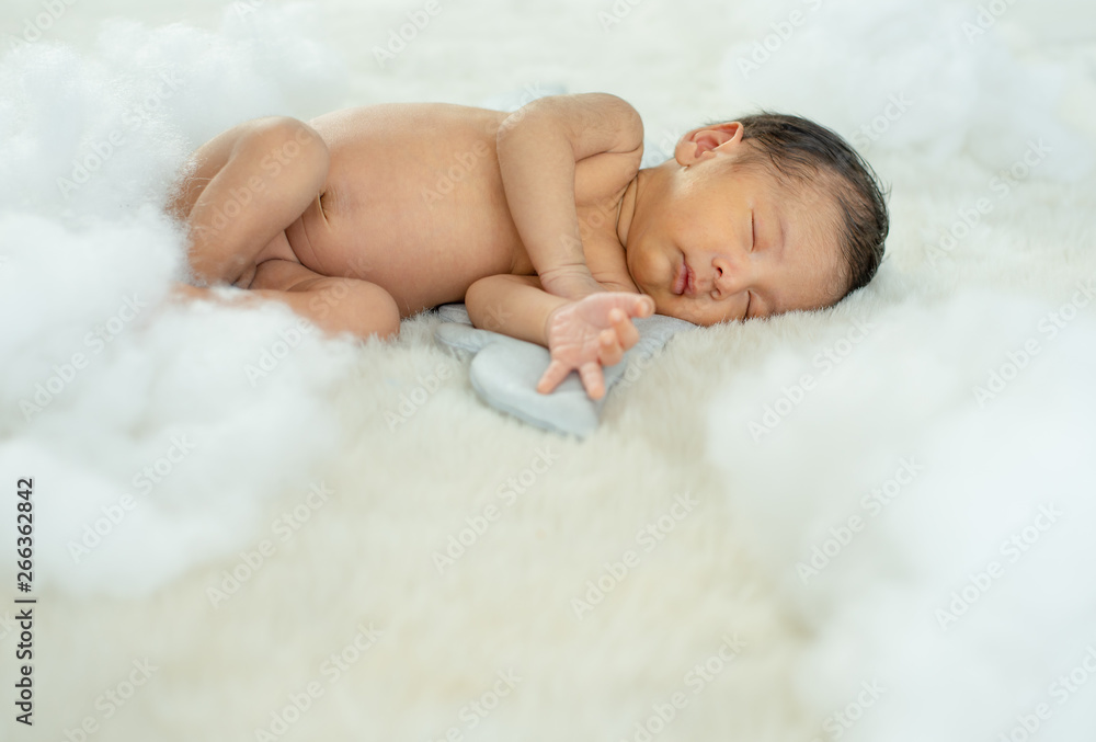 Little newborn baby is sleeping on white bed with wing accessory and fluffy pandas Little newborn baby is sleeping on white bed with wing accessory and fluffy pandas