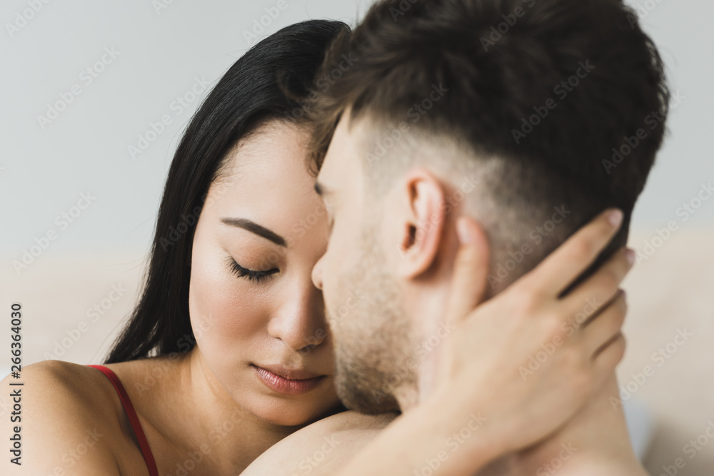 selective focus of beautiful, pensive asian woman embracing boyfriend with closed eyes selective focus of beautiful, pensive asian woman embracing boyfriend with closed eyes