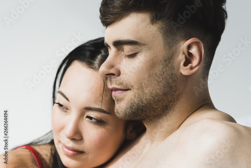 attractive, pensive asian woman near handsome boyfriend with closed eyes on grey © LIGHTFIELD STUDIOS