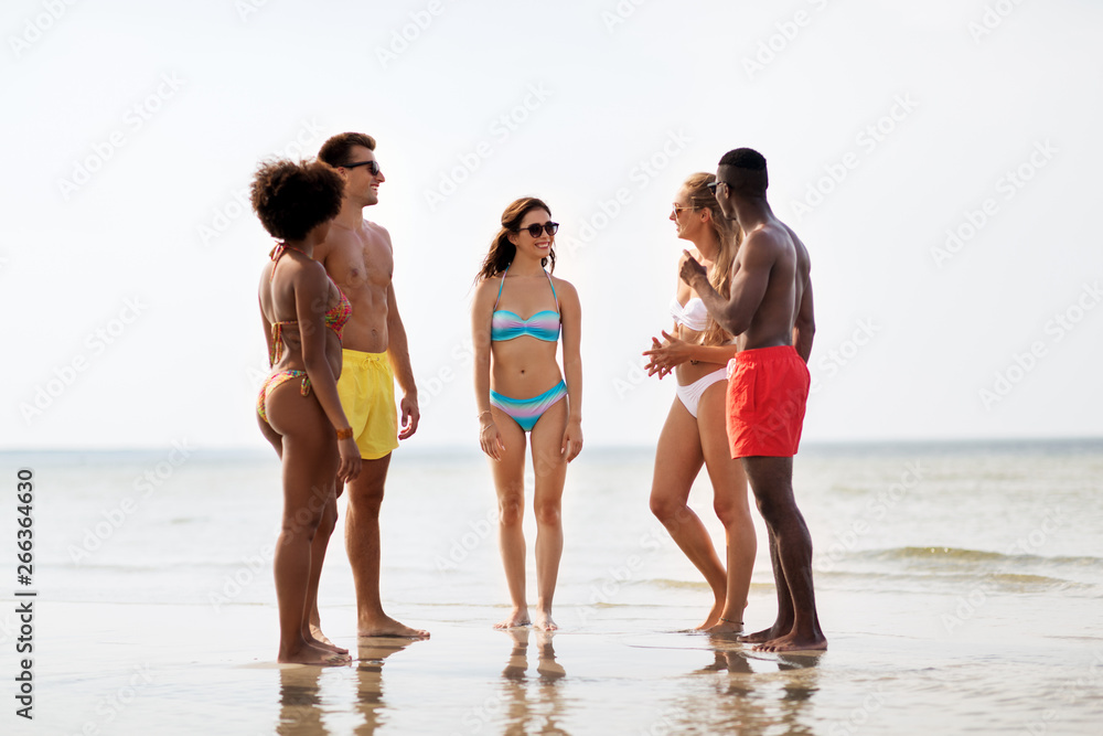 friendship, summer holidays and people concept - happy friends hugging on beach
