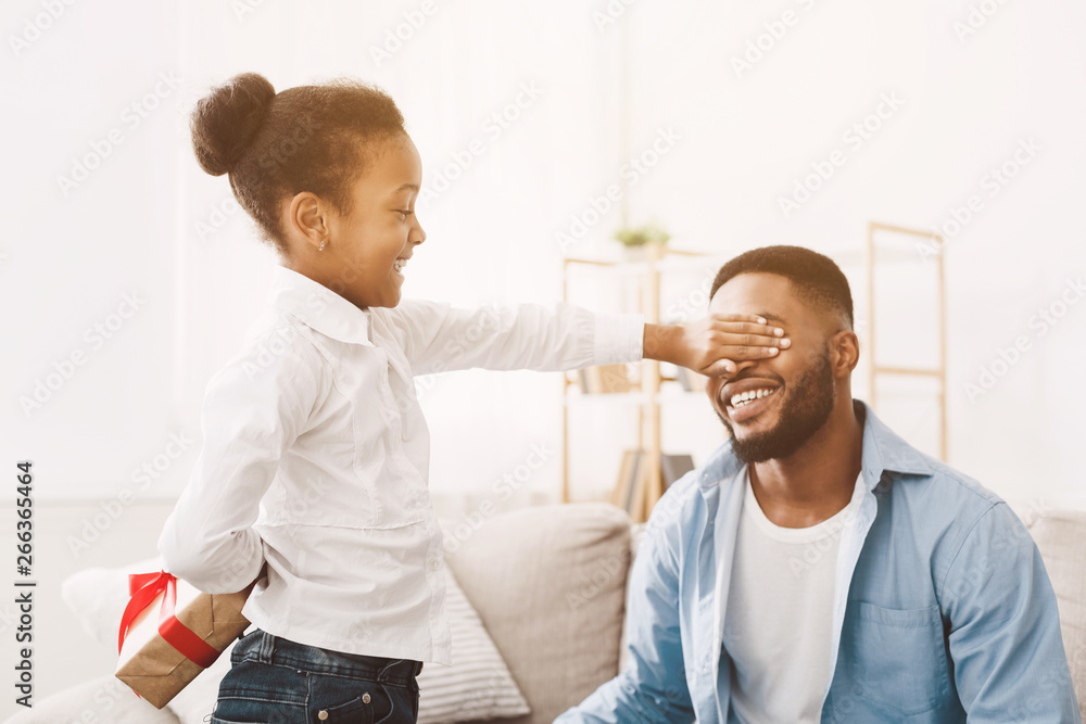 Obraz premium Little girl giving present to daddy, closing his eyes