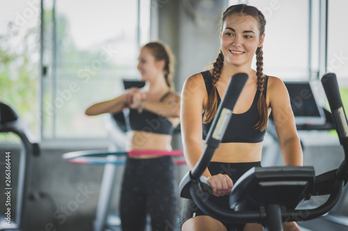Attractive woman biking in the gym, exercising legs doing cardio workout cycling bikes. Fitness club with training exercise bikes. Fitness, Healthy, Sport, Lifestyle concept.