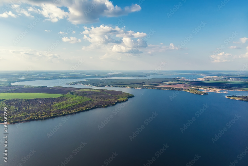 Scenic aerial panoramic landscape of Oskol river curve in eastern Europe with green forest at banks and blue cloudy sky. Natural scenic summer travel panorama wallpaper. Aerial drone shot