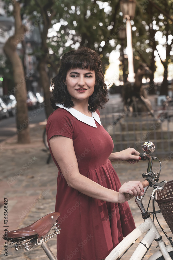 Obraz premium A smiling woman in a red dress with a bike 