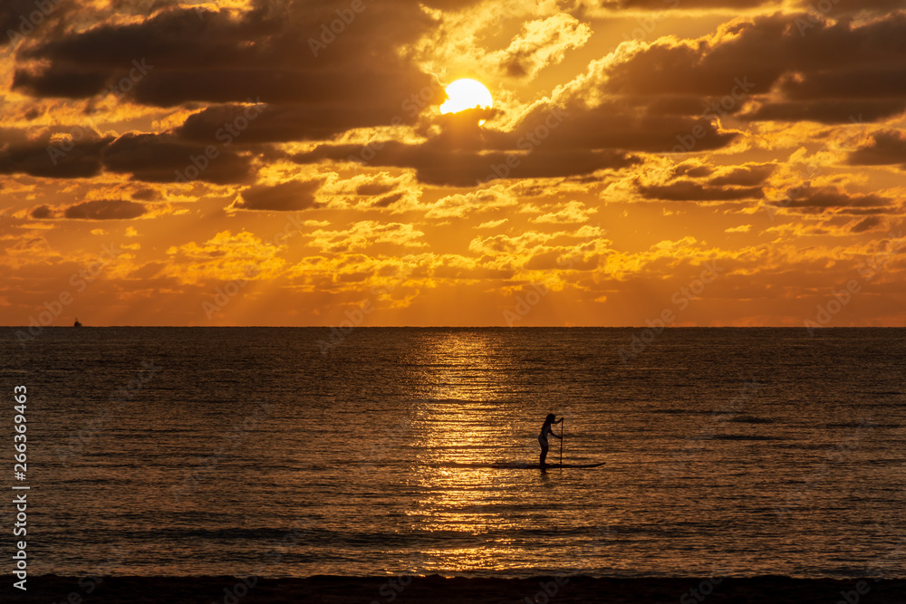 silhouette of a woman on a paddle board on the ocean at sunrise