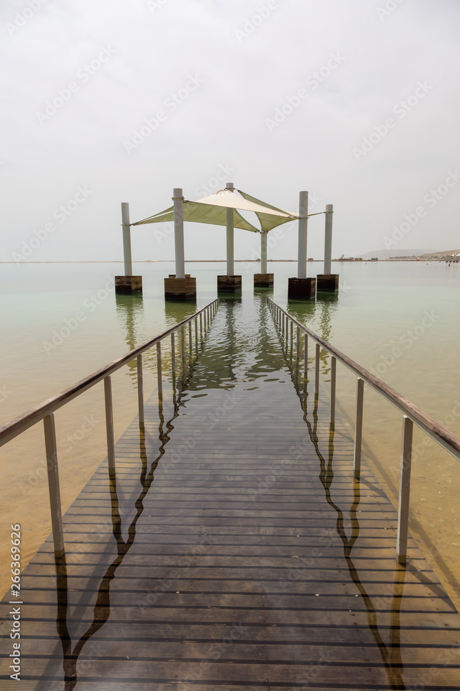 Obraz premium Path leading into the water on a sandy beach at the Dead Sea during a sunny day. Taken in Ein Bokek, Israel.