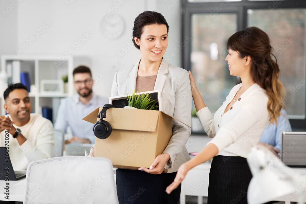 business, job and quit concept - new female office worker with box of personal stuff and happy smiling colleague business, job and quit concept - new female office worker with box of personal stuff and happy smiling colleague