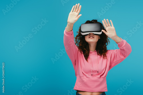 curly girl wearing virtual reality headset while gesturing on blue © LIGHTFIELD STUDIOS