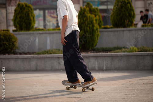 Fototapeta Naklejka Na Ścianę i Meble -  Young guys in stylish clothes ride a skateboard in the park.