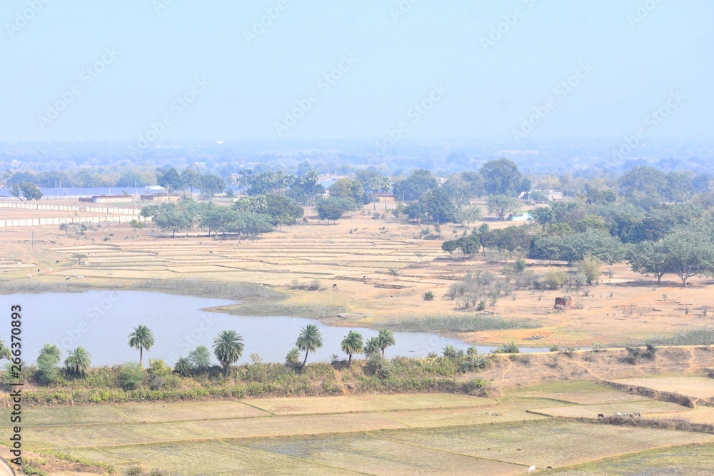 Natural rural landscape of India with a scenic pond, horizontal view in the villages of Deoghar, Santhal Pargana, Jharkhand, INDIA - Tourism concept with beautiful distant blue horizon. 