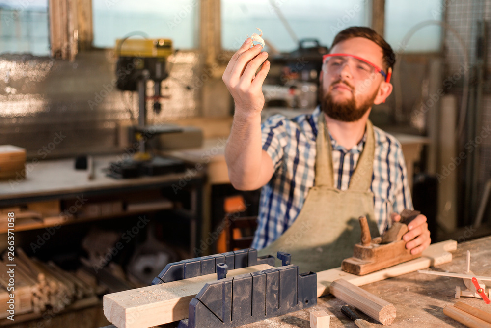 Working days of a professional carpenter in a home workshop, a craftsman at his workplace holds sawdust in his hand Working days of a professional carpenter in a home workshop, a craftsman at his workplace holds sawdust in his hand