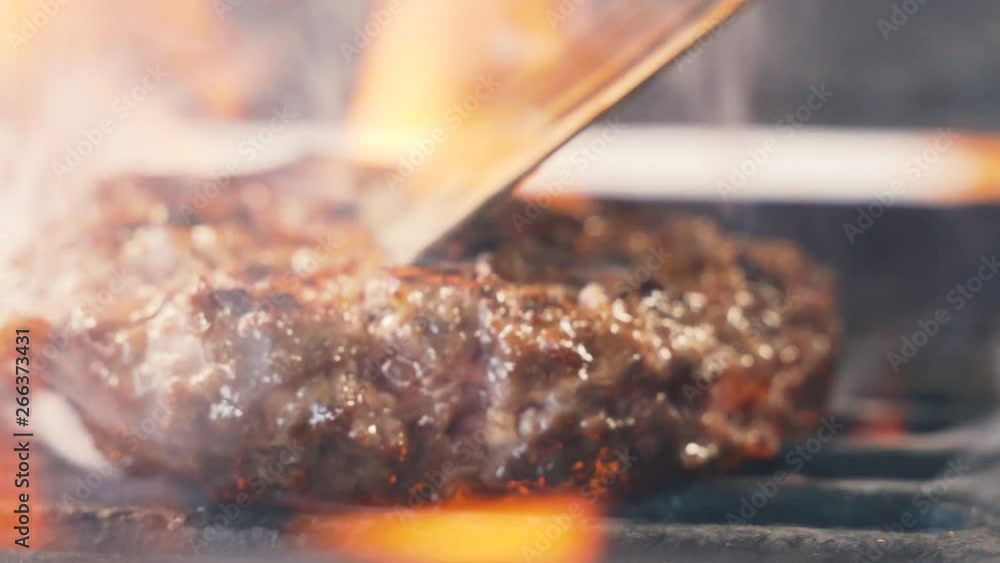 Vidéo Stock Chief cooked meat for a burger on the grill turning using ...