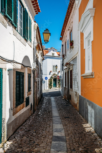 Small narrow cobblestone alley street between whitewashed houses and walls in old town Cascais, Portugal © Alexandre Rotenberg