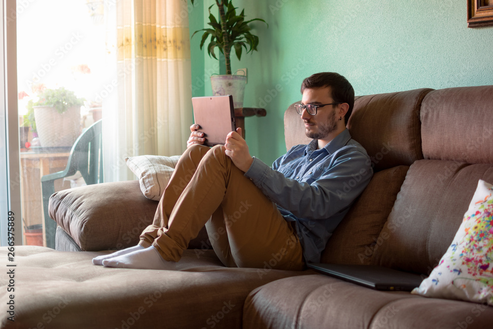 Fototapeta premium Young man with tablet on sofa at home