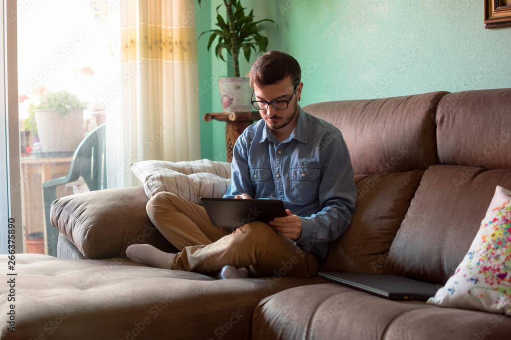 Young man with tablet on sofa at home Young man with tablet on sofa at home