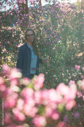 Portrait of young beauty woman in purple rhododendron flowers. Blooming rhododendron - maralnik in Altai mountain forest in the spring. photo