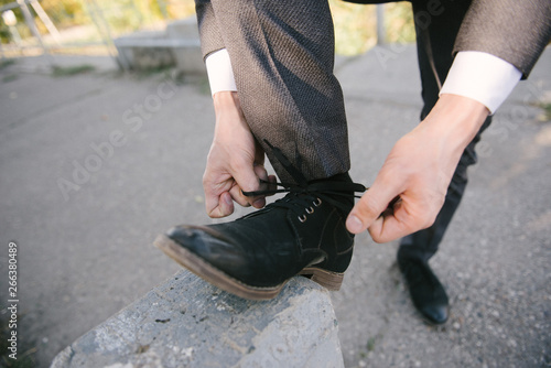A man in a suit puts shoes on his feet.