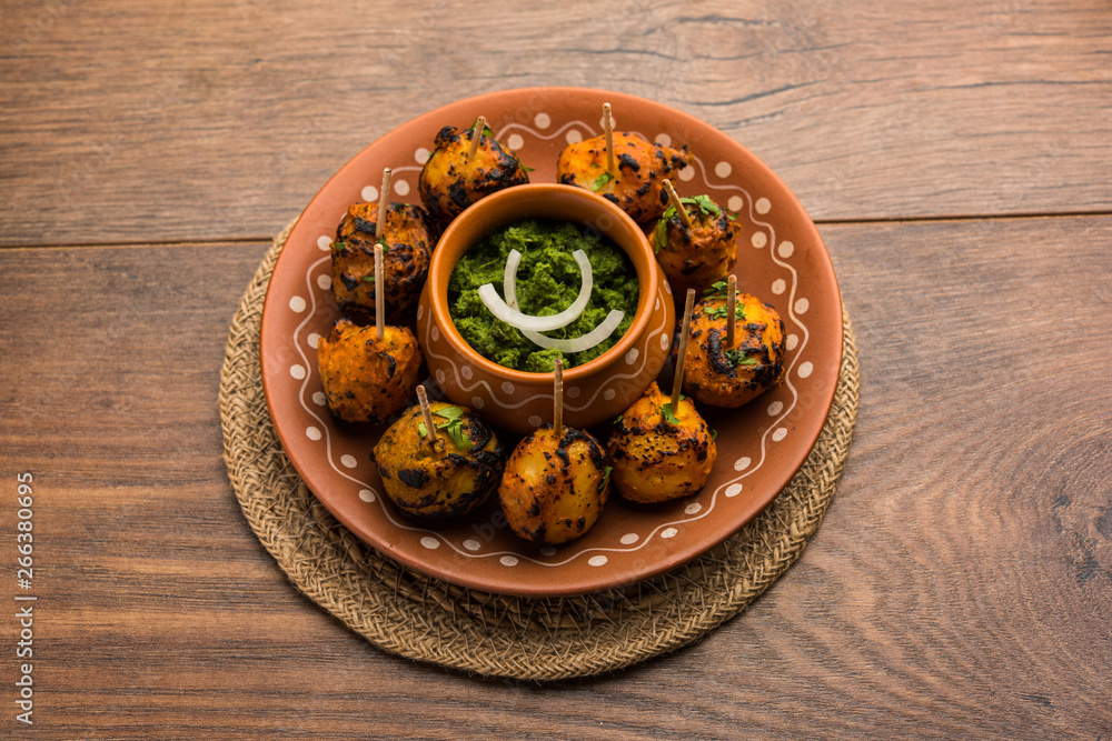 Tandoori aloo are roasted potatoes with Indian spices. It's a party appetiser served with green chutney. selective focus