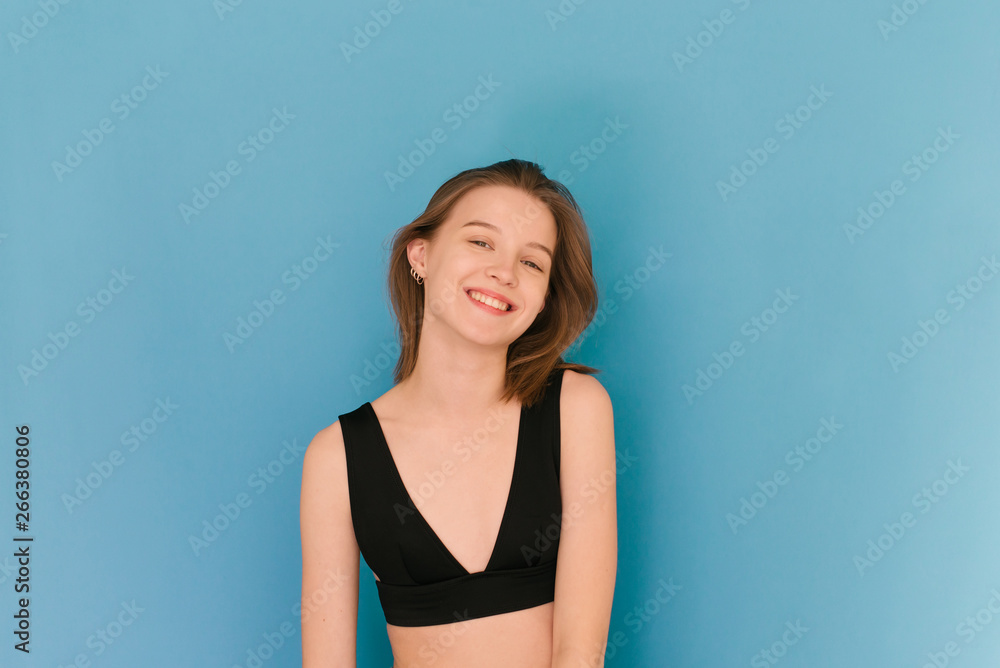 Smiling model poses on a blue background, wears a bra, looks into the camera and smiles. The model shows its emotions. Model tests for the agency. Smiling model poses on a blue background, wears a bra, looks into the camera and smiles. The model shows its emotions. Model tests for the agency.