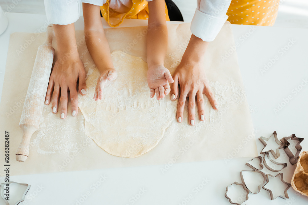 top view of mother and daughter with dough, rolling pin and dough molds on table top view of mother and daughter with dough, rolling pin and dough molds on table