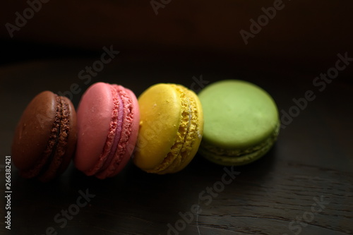 Multi-colored macaroons on a wooden tray. Pink, yellow and green macaroon.