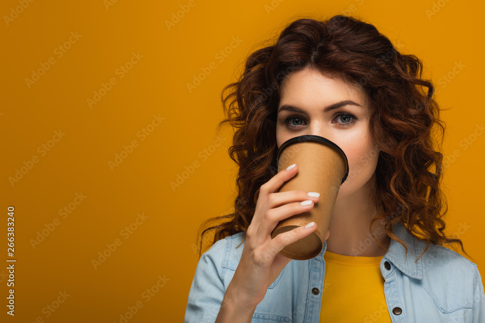 curly redhead girl covering face with paper cup while drinking on orange curly redhead girl covering face with paper cup while drinking on orange