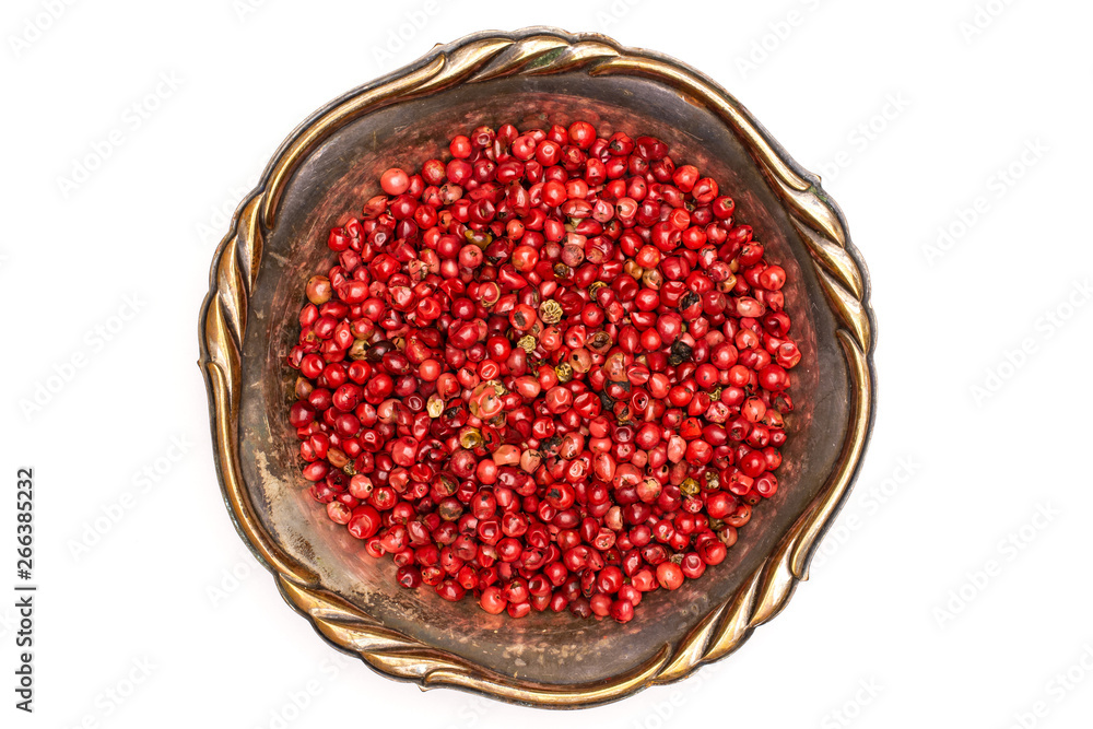 Lot of whole peruvian pink pepper in old iron bowl flatlay isolated on white background Lot of whole peruvian pink pepper in old iron bowl flatlay isolated on white background
