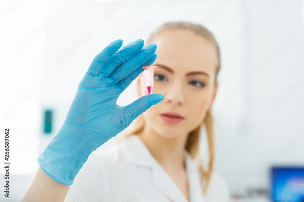 Hand of a lab technician holding a mini test tube with blood sample for analysis. Hand of a lab technician holding a mini test tube with blood sample for analysis.