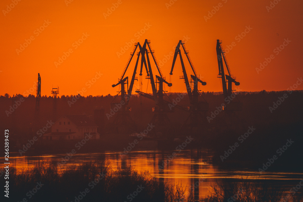 silhouettes of port cranes on the background of a beautiful order