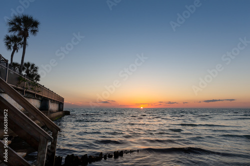 Ocean Sunset with Sea Wall and Palm Trees in Foreground