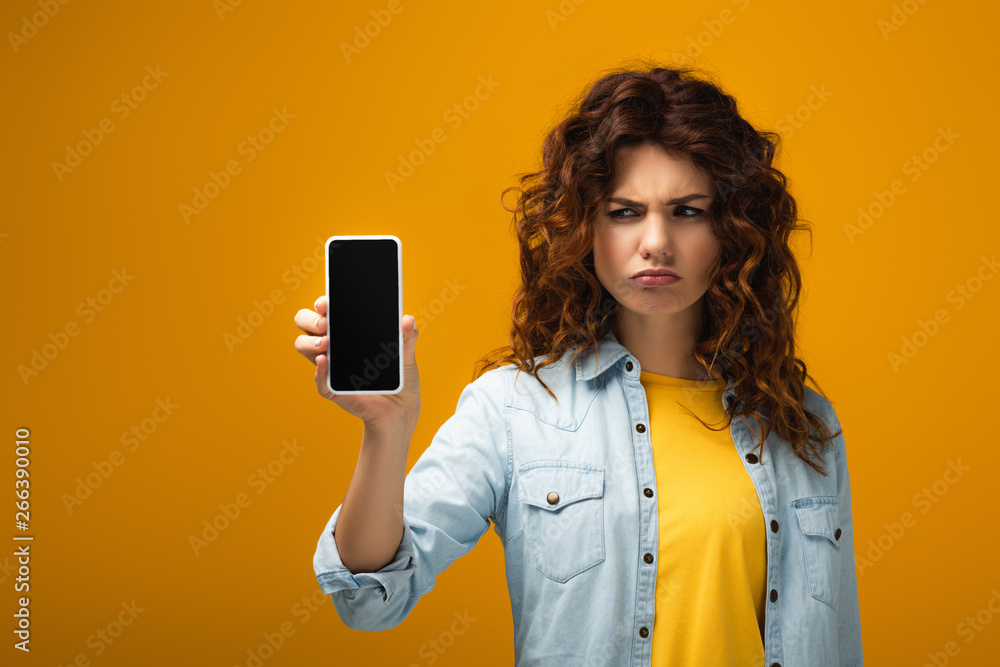 upset woman holding smartphone with blank screen on orange upset woman holding smartphone with blank screen on orange