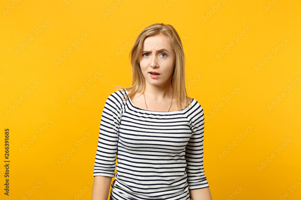 Portrait of perplexed puzzled young woman in striped clothes standing looking camera isolated on yellow orange wall background in studio. People sincere emotions lifestyle concept. Mock up copy space. Portrait of perplexed puzzled young woman in striped clothes standing looking camera isolated on yellow orange wall background in studio. People sincere emotions lifestyle concept. Mock up copy space.