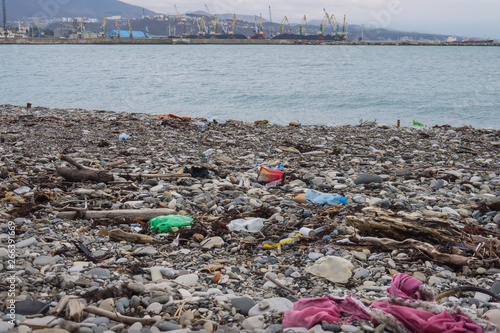 spilled garbage on a pebble beach in front  of the cargo port