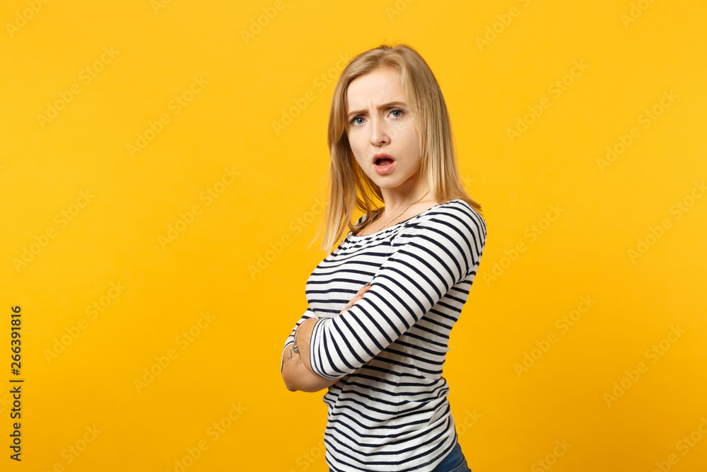 Portrait of irritated young woman in striped clothes looking camera holding hands crossed isolated on yellow orange background in studio. People sincere emotions lifestyle concept. Mock up copy space. Portrait of irritated young woman in striped clothes looking camera holding hands crossed isolated on yellow orange background in studio. People sincere emotions lifestyle concept. Mock up copy space.