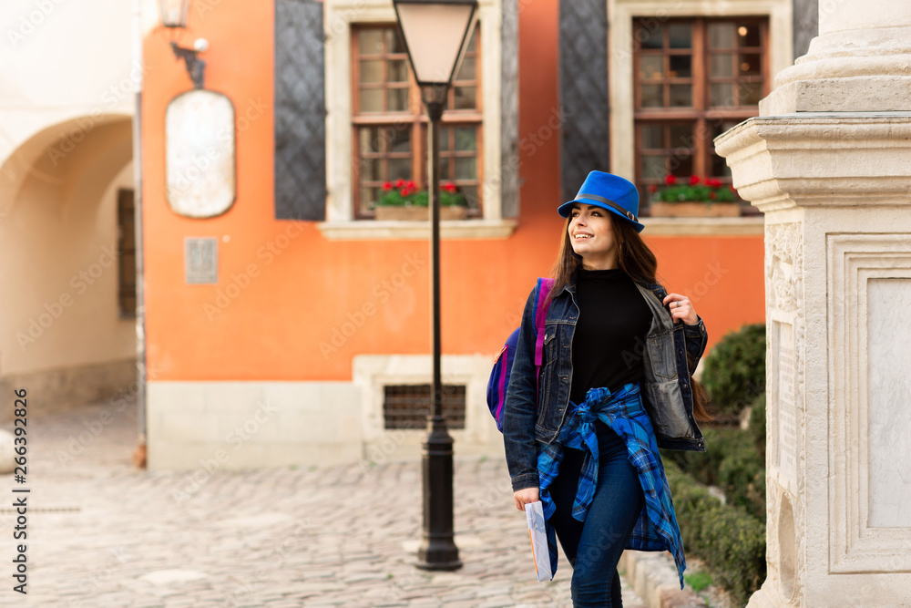 A young tourist walking in the old courtyard, near the red wall in Lviv. Ukraine
