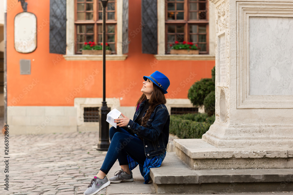 A young tourist sits on the stairs in the old courtyard, near the red wall in Lviv. Ukraine A young tourist sits on the stairs in the old courtyard, near the red wall in Lviv. Ukraine