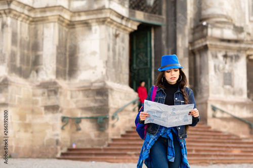 Young woman standing near the church in old city Lviv, and holds a map in hand. Ukraine © Olha