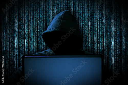 Fototapeta Naklejka Na Ścianę i Meble -  hacker with red glowing mask behind notebook laptop in front of blue source binary code background internet cyber hack attack concept