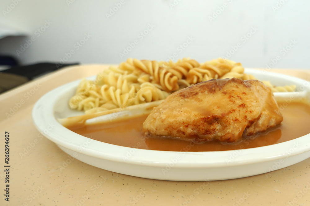 Chicken breast served with noodles and gravy on a tray Chicken breast served with noodles and gravy on a tray