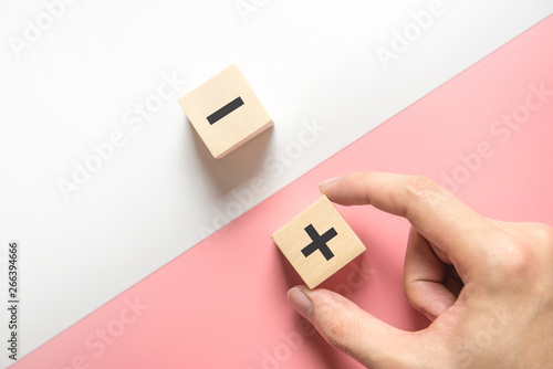 Pros and cons concept, Hand choose wood blog with plus and minus on white and pink background, flat lay, copy space, top view.