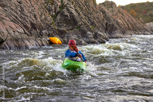 Man in green kayak fights with rapids of fast mountain river among the rocks. Whitewater kayaking, extreme water sport. © watcherfox