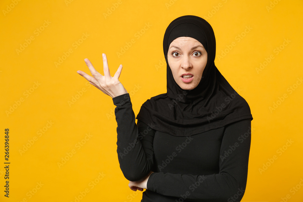 Sad upset crying confused young arabian muslim woman in hijab black clothes posing isolated on yellow wall background, studio portrait. People religious Islam lifestyle concept. Mock up copy space. Sad upset crying confused young arabian muslim woman in hijab black clothes posing isolated on yellow wall background, studio portrait. People religious Islam lifestyle concept. Mock up copy space.
