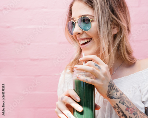 Happy blonde girl drinking a healthy green juice photo