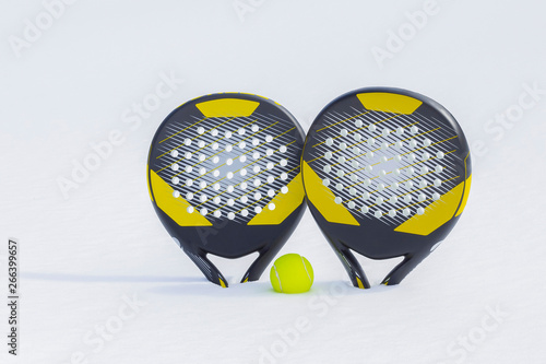 The ball and two beach tennis rackets are thrust in a snow snowdrift.