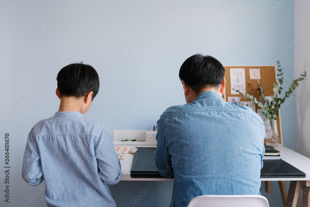 Father working at home while son plays Father working at home while son plays