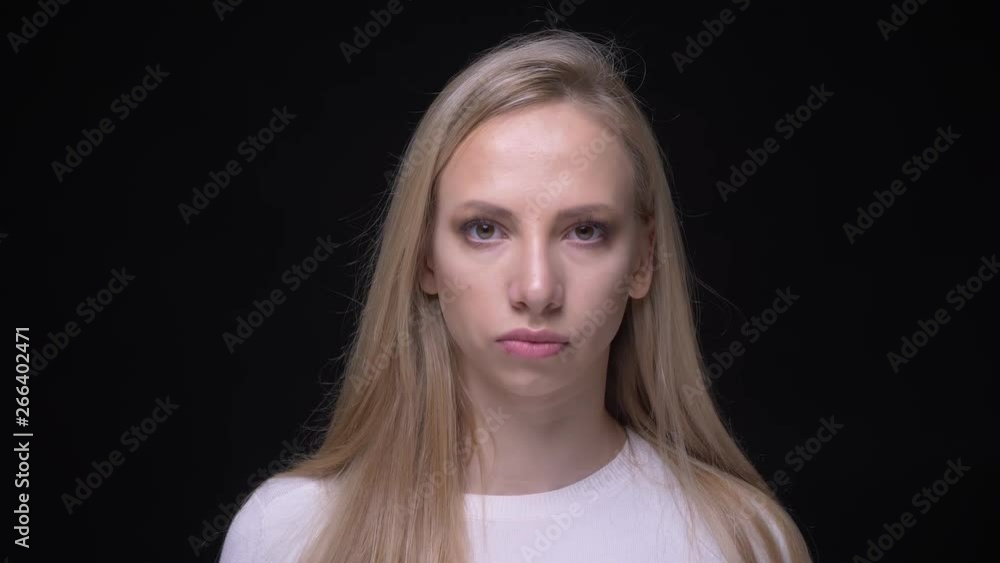 Closeup portrait of young pretty blonde female waving her head saying no looking at camera with background isolated on black Closeup portrait of young pretty blonde female waving her head saying no looking at camera with background isolated on black