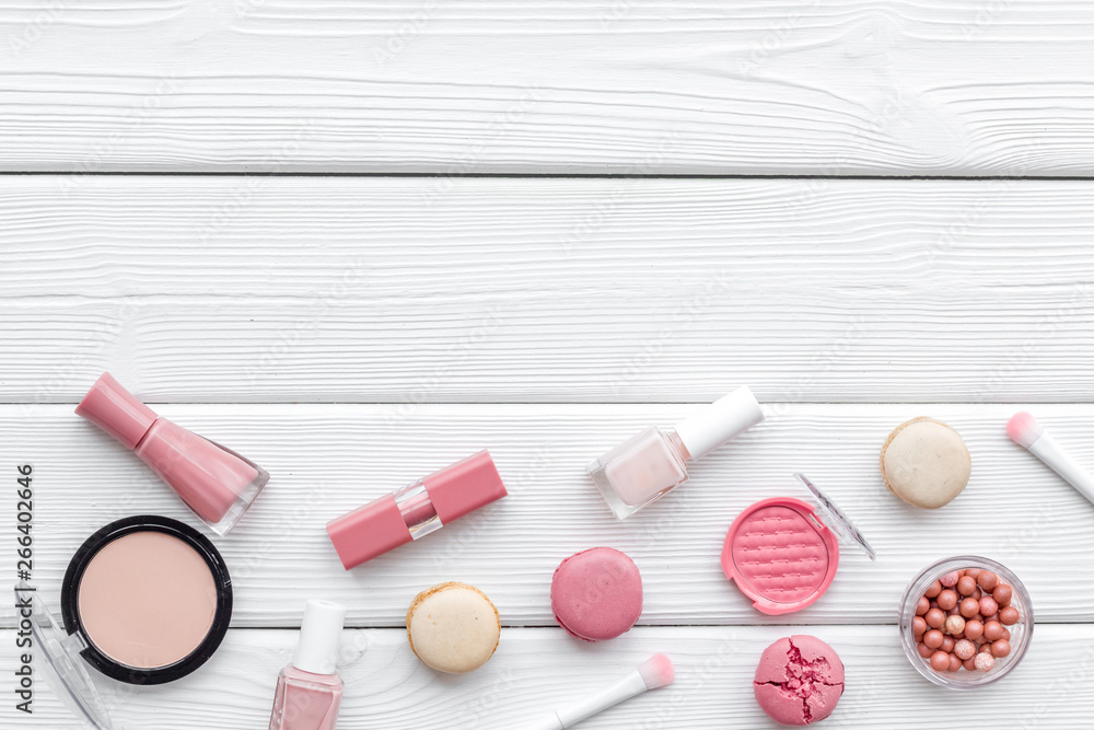 Naklejka premium make-up accessories, fashion stylish cosmetics and macaroon on white wooden desk background top view copy space